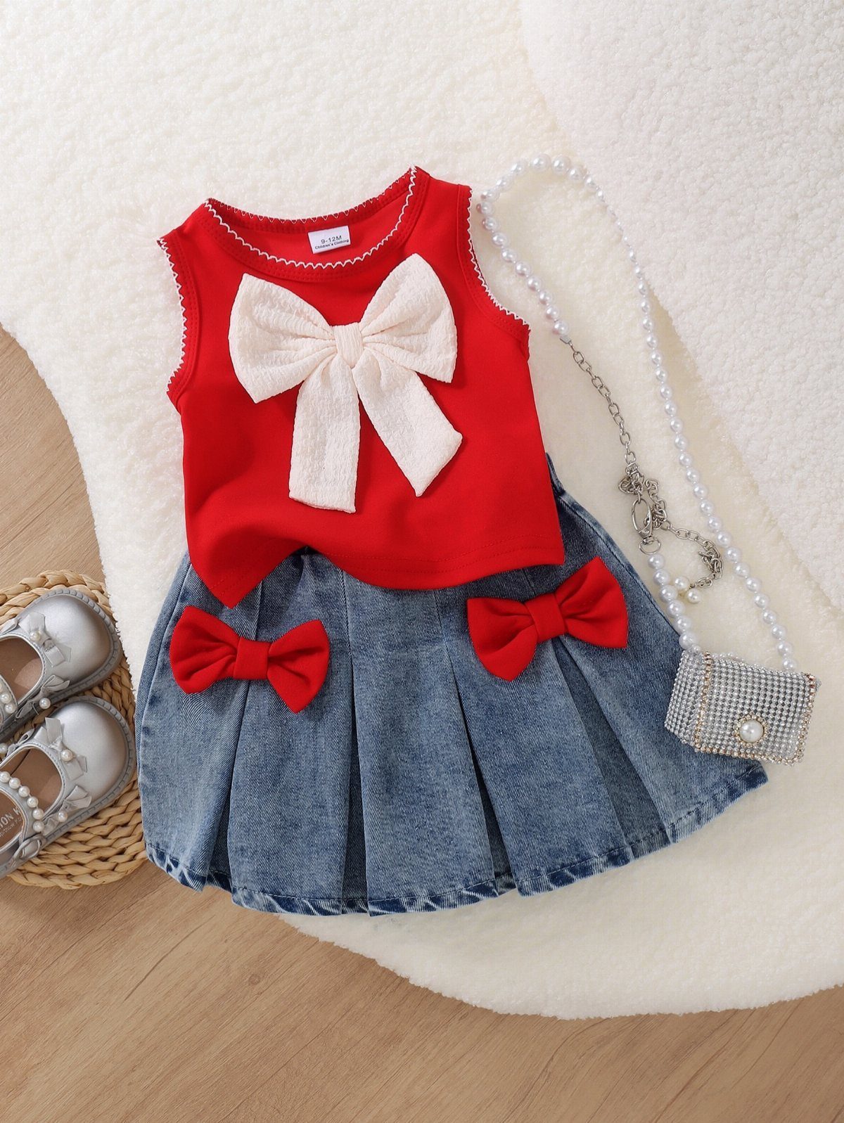 Red sleeveless top with a large white bow and a denim pleated skirt with red bows.