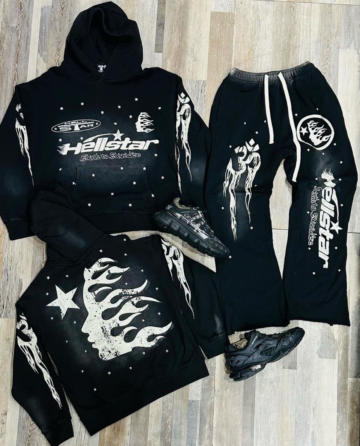 Hellstar black streetwear clothing set with white graphic prints and black sneakers on a wooden floor.