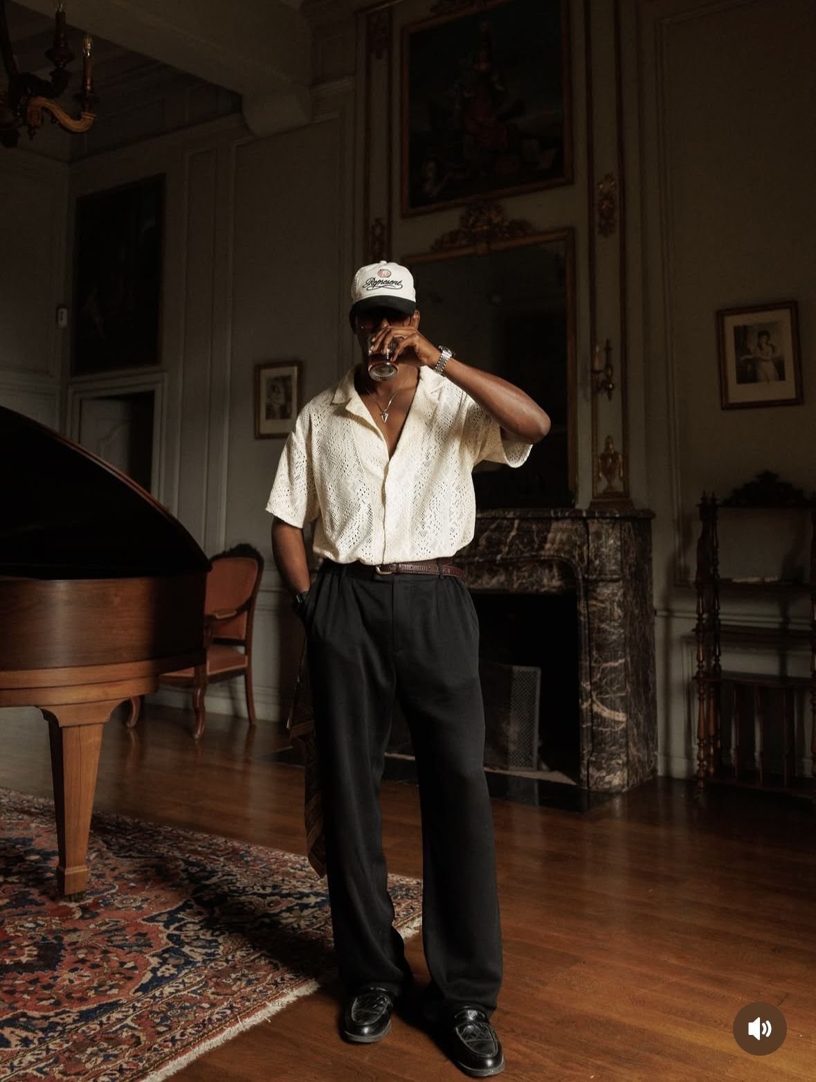 Man in stylish smart-casual attire standing in a classic room with a grand piano.