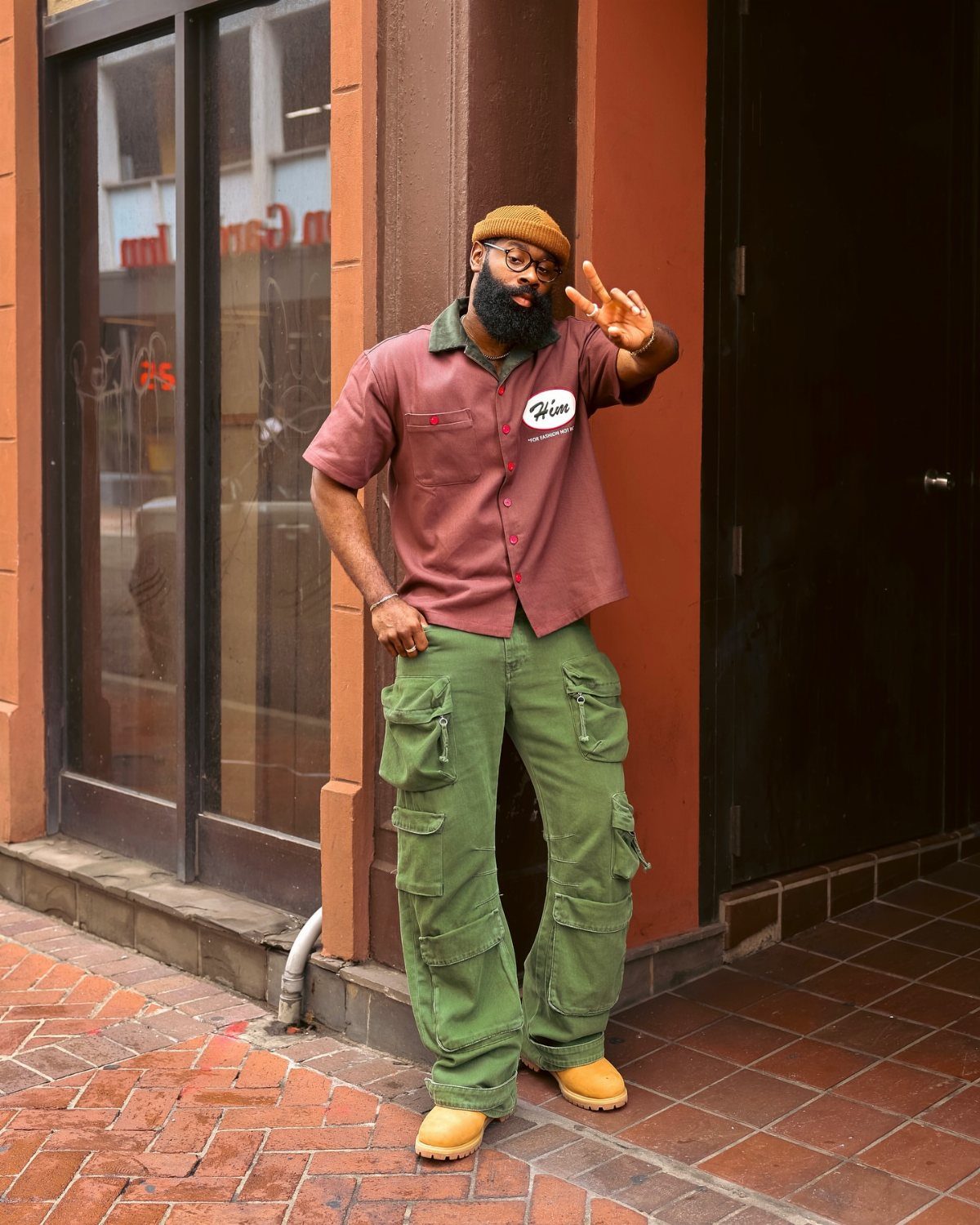 Man in maroon shirt and baggy green cargo pants wearing tan work boots.