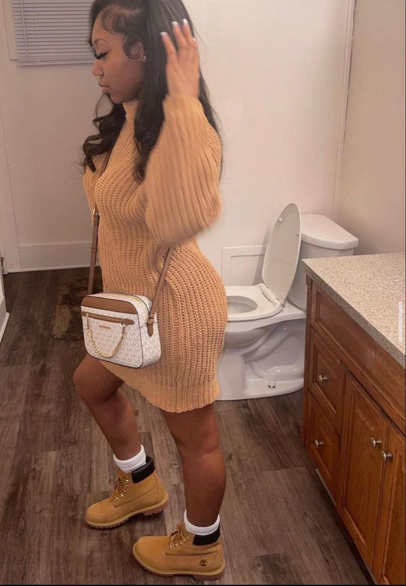 Woman wearing a tan knit sweater dress paired with tan Timberland boots and white socks.