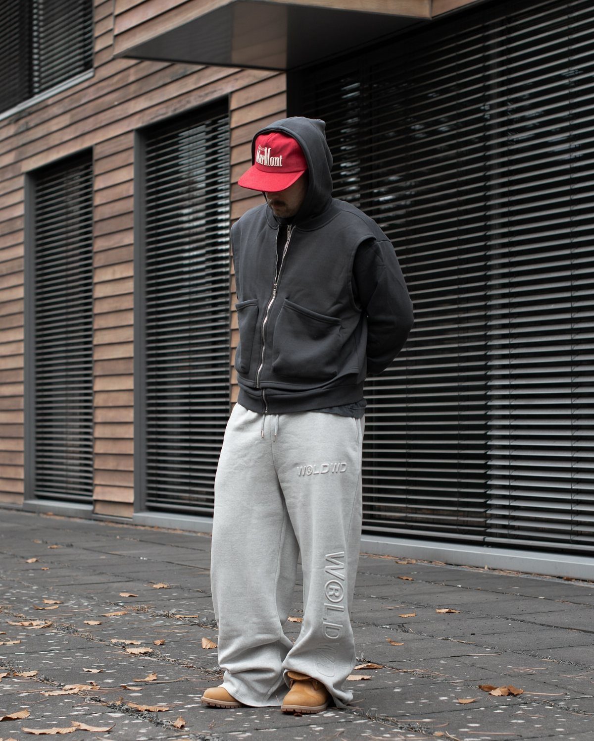 Person wearing grey sweatpants and tan boots standing on a paved sidewalk outdoors.