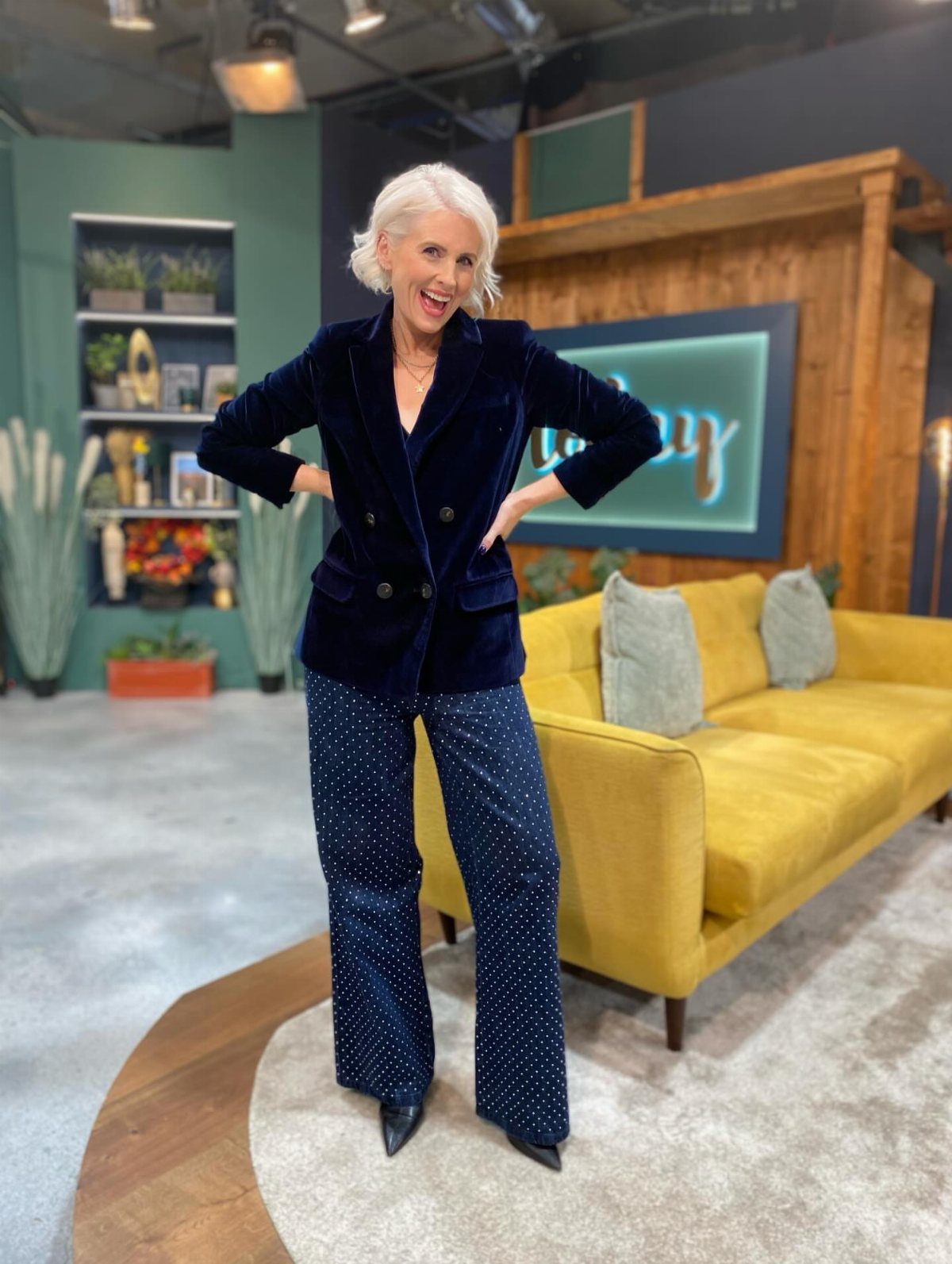 Woman posing in a navy blue velvet blazer and polka dot wide-leg trousers.